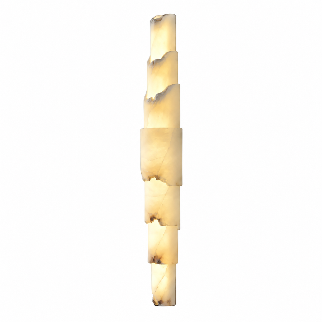 A modern vertical wall sconce made of stacked irregular rectangular stone sections, glowing with a warm cream and light brown marbled light against a plain white background.