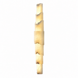 A modern vertical wall sconce made of stacked irregular rectangular stone sections, glowing with a warm cream and light brown marbled light against a plain white background.