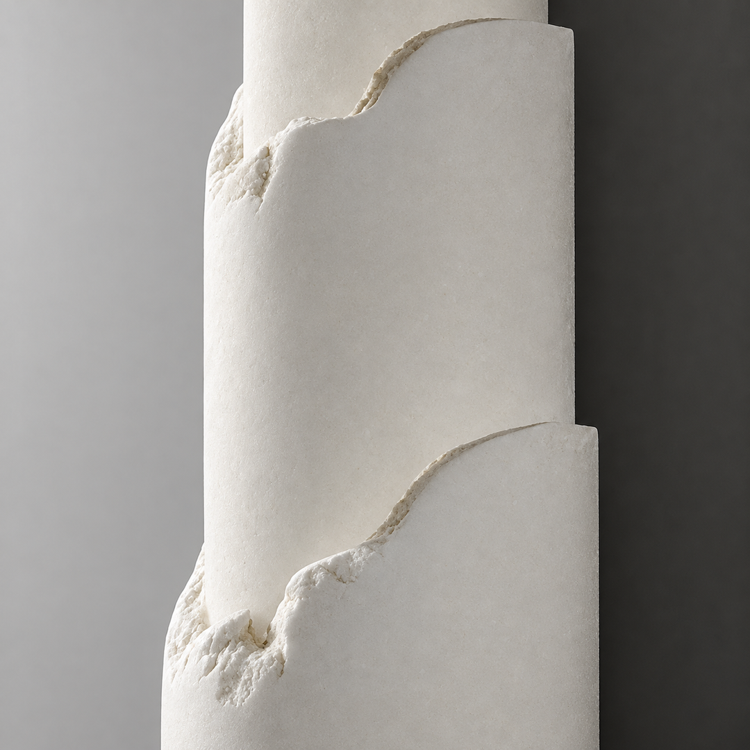 Close-up of an off-white alabaster wall sconce with curved layered edges mounted on a gray wall.