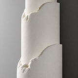 Close-up of an off-white alabaster wall sconce with curved layered edges mounted on a gray wall.