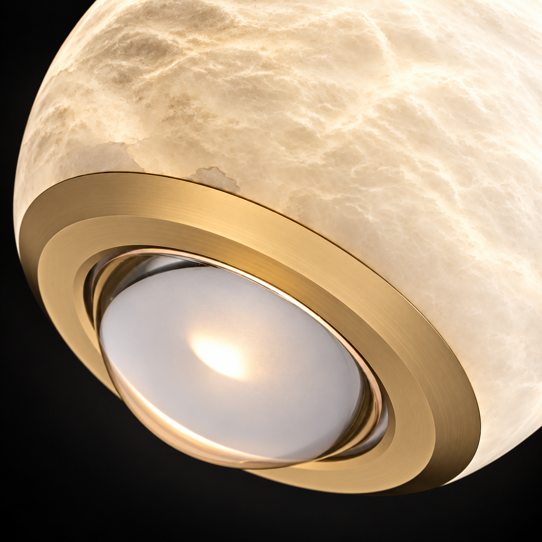 A pendant light close-up shows the illuminated alabaster globe, gold-colored lower trim, and circular underside opening against a black background.