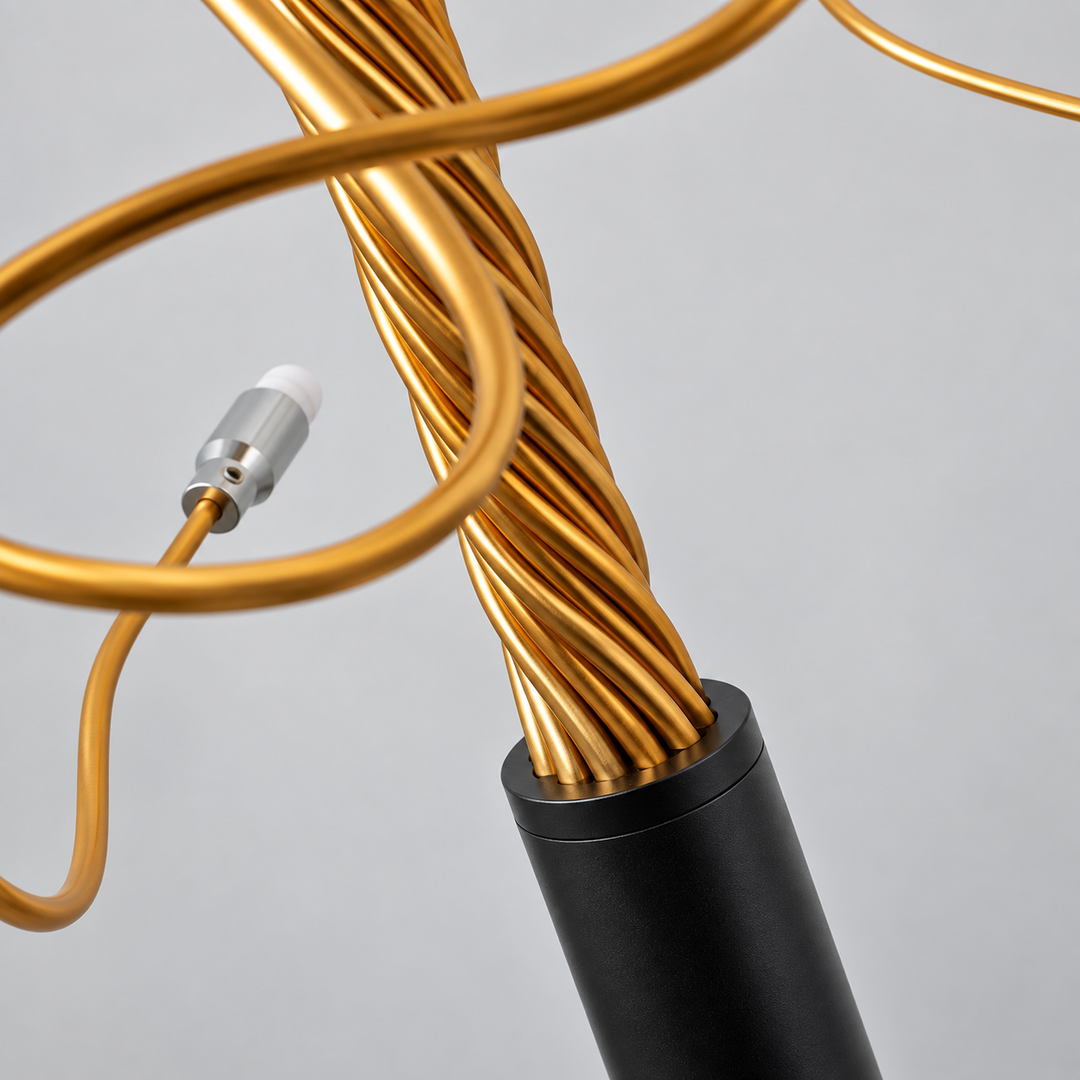 Close-up of the tree branch floor lamp showing twisted gold-tone aluminum branches rising from a black cylindrical base against a plain light background.