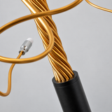 Close-up of the tree branch floor lamp showing twisted gold-tone aluminum branches rising from a black cylindrical base against a plain light background.