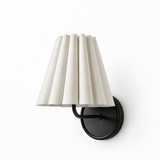 A modern wall-mounted sconce with a pleated off-white fabric shade and a matte black metal wall mount, shown against a plain white background.