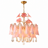 A pink and gold chandelier featuring translucent pink glass bell-shaped shades, pink flower accents, and hanging crystal drops on a white background.
