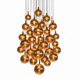 A cluster chandelier featuring multiple amber-tinted glass globe bulbs suspended from a central brass-toned metal frame against a solid white background.