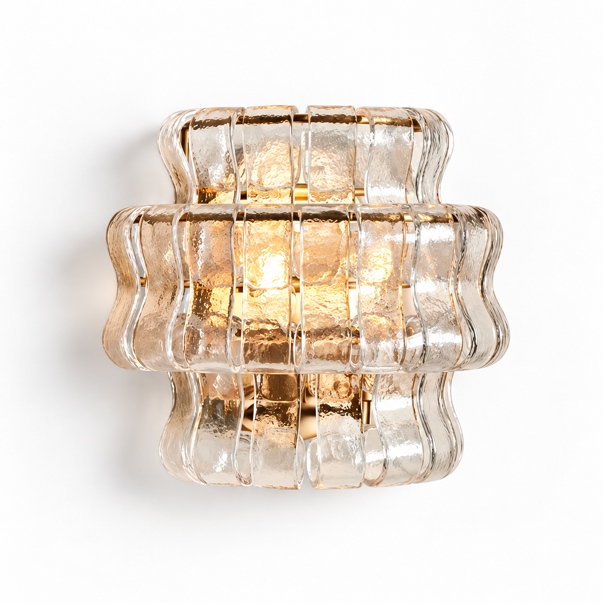 A modern wall sconce featuring a textured, ribbed clear glass shade with a warm gold metallic frame and glowing light inside, shown against a plain white background.