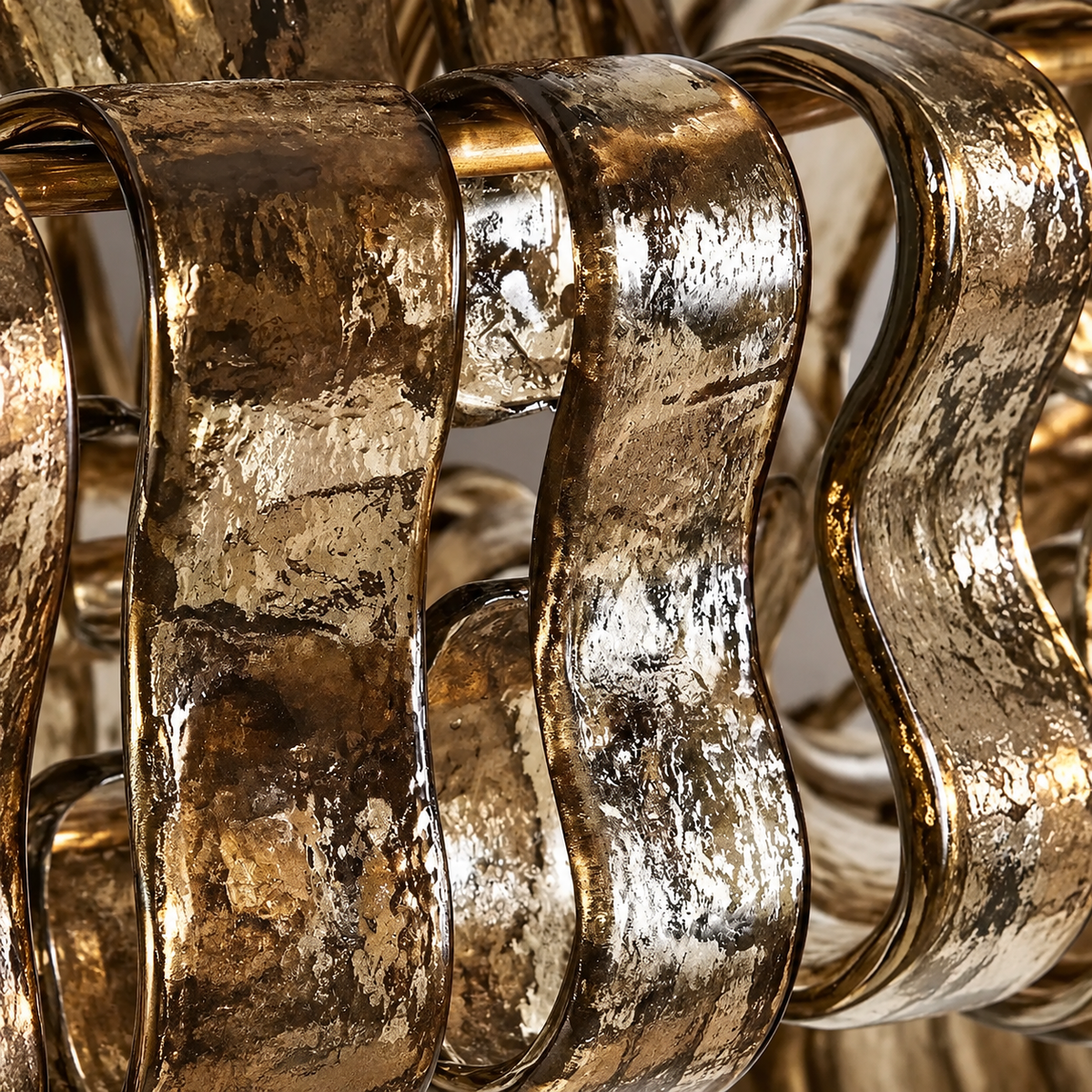Close-up of the wall sconce's handmade rippled glass bands, curving loops in a mottled amber and silver finish.