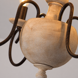 Close-up of the chandelier's distressed cream wooden center body and curved dark iron arms.