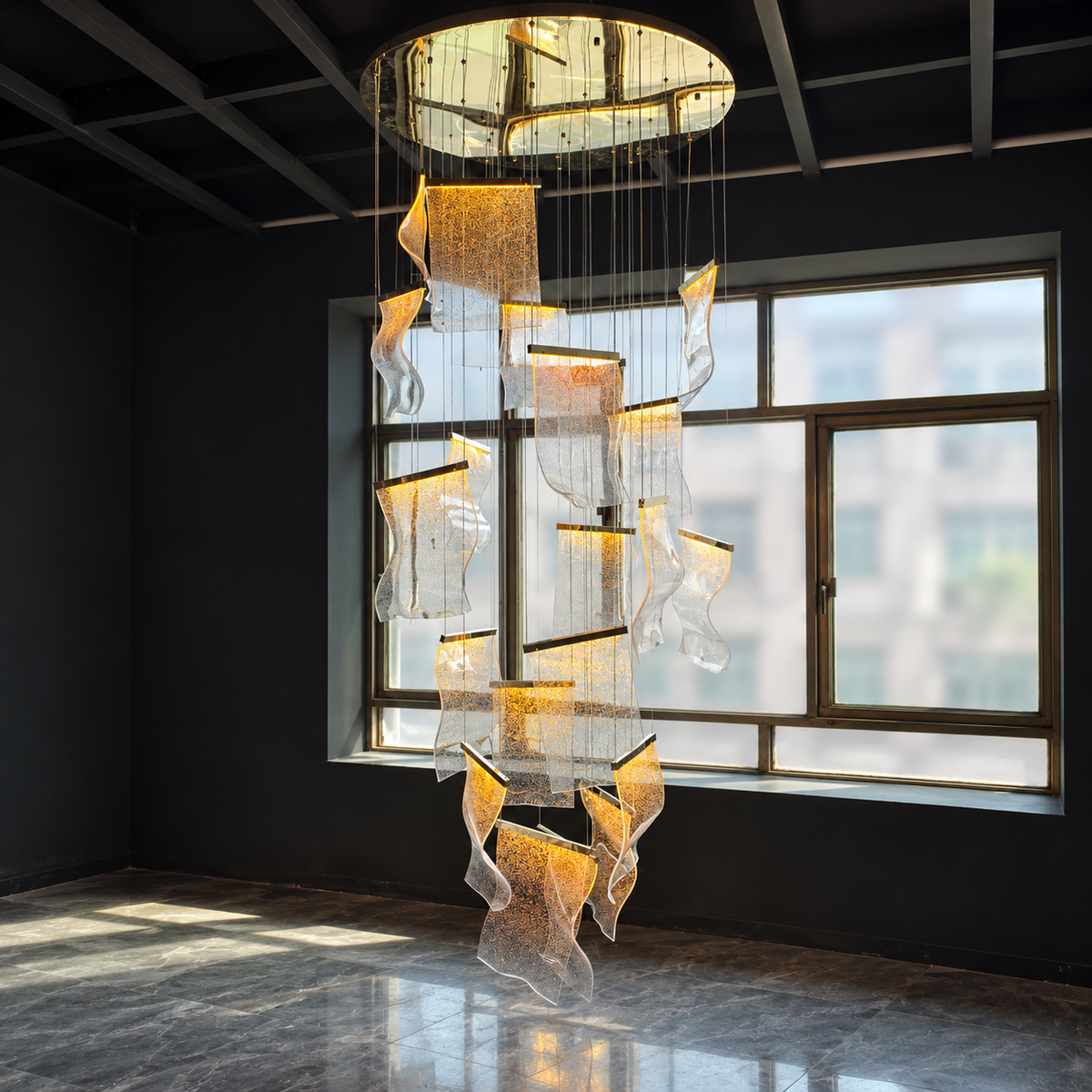 A large modern chandelier with multiple cascading, translucent wave-like glass panels illuminated from within, hanging in a spacious dark room with a large window and polished floor.
