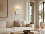 Modern living room with a beige sofa, decorative pillows, and a wall sconce.