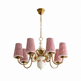 Gold-tone chandelier with curved arms, red-and-white patterned shades, a white central stem, and sunburst details against a white background.