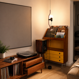 Illuminated red floor lamp beside a wooden record cabinet and turntable in a living room.