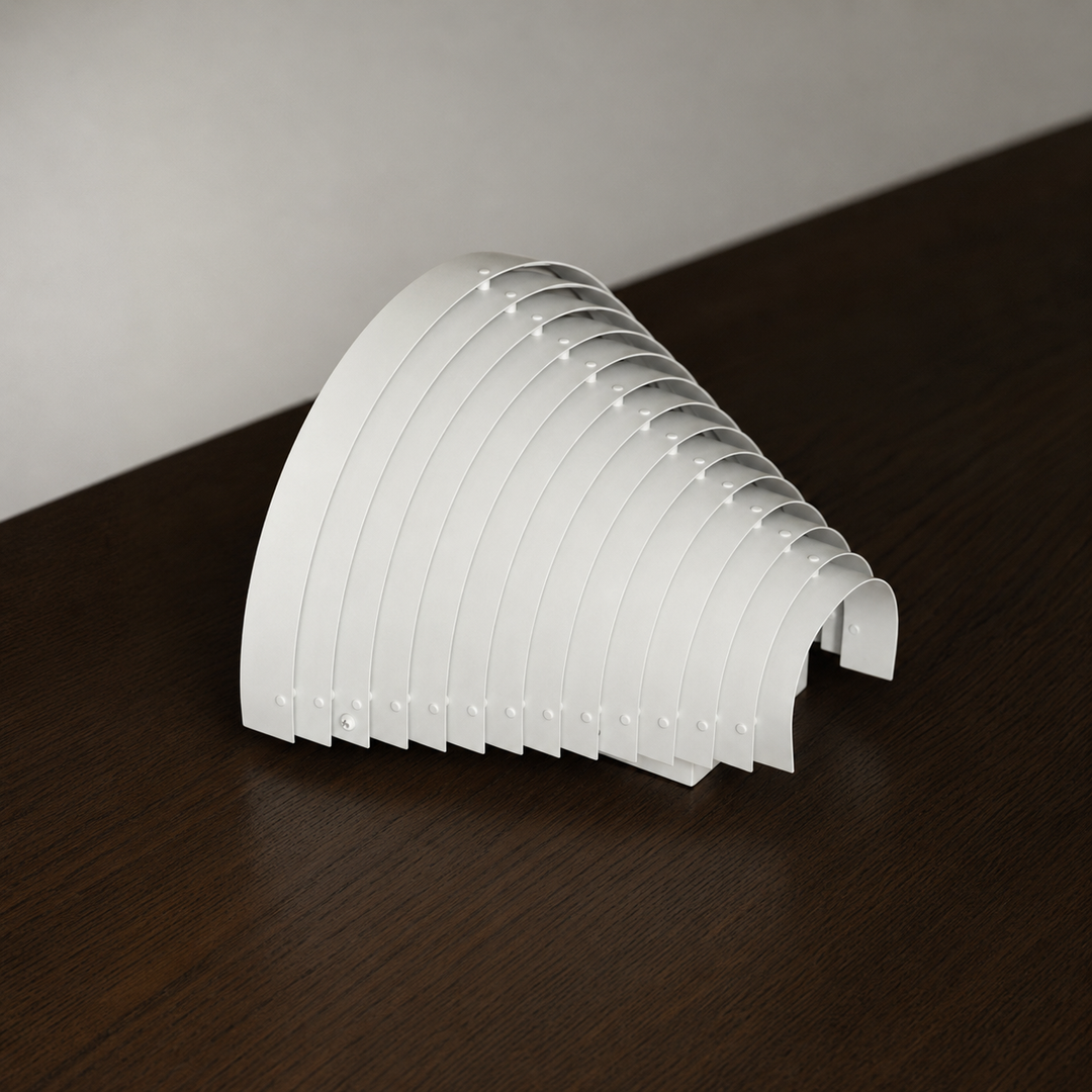 White steel wall sconce resting on a dark wooden surface, showing its curved overlapping slats from an angled side view.