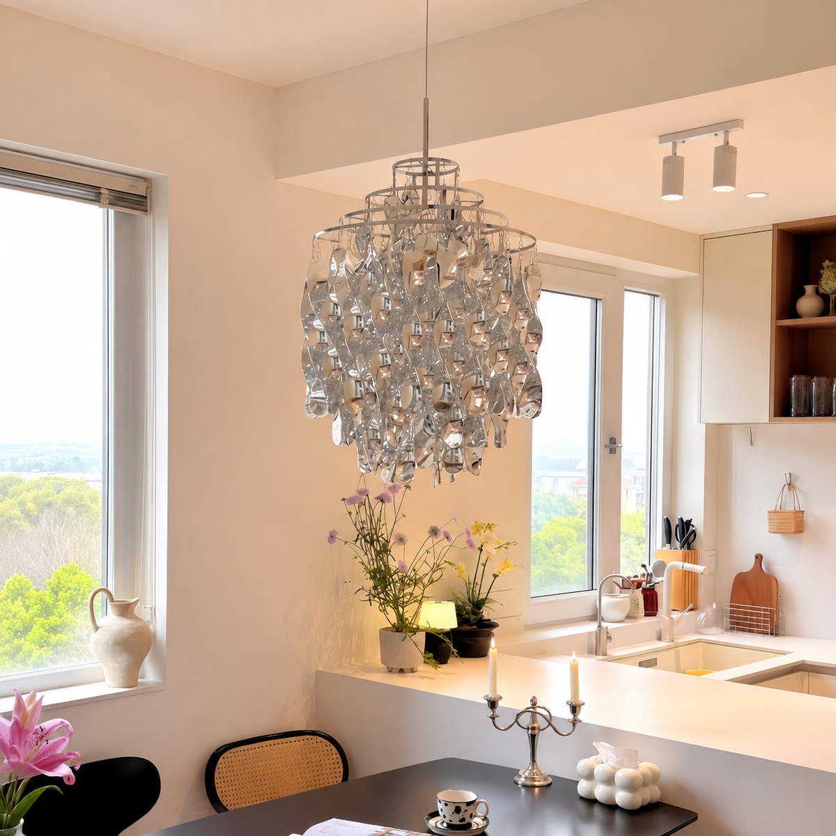 Chrome acrylic spiral pendant light hanging above a dark dining table beside a bright kitchen with white counters.
