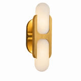 Gold-toned wall sconce with two glowing white rounded shades and an oval backplate, shown against a white background.