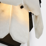 Close-up of a modern wall sconce with translucent white stone or acrylic geometric panels and a dark metal frame, illuminated from within.
