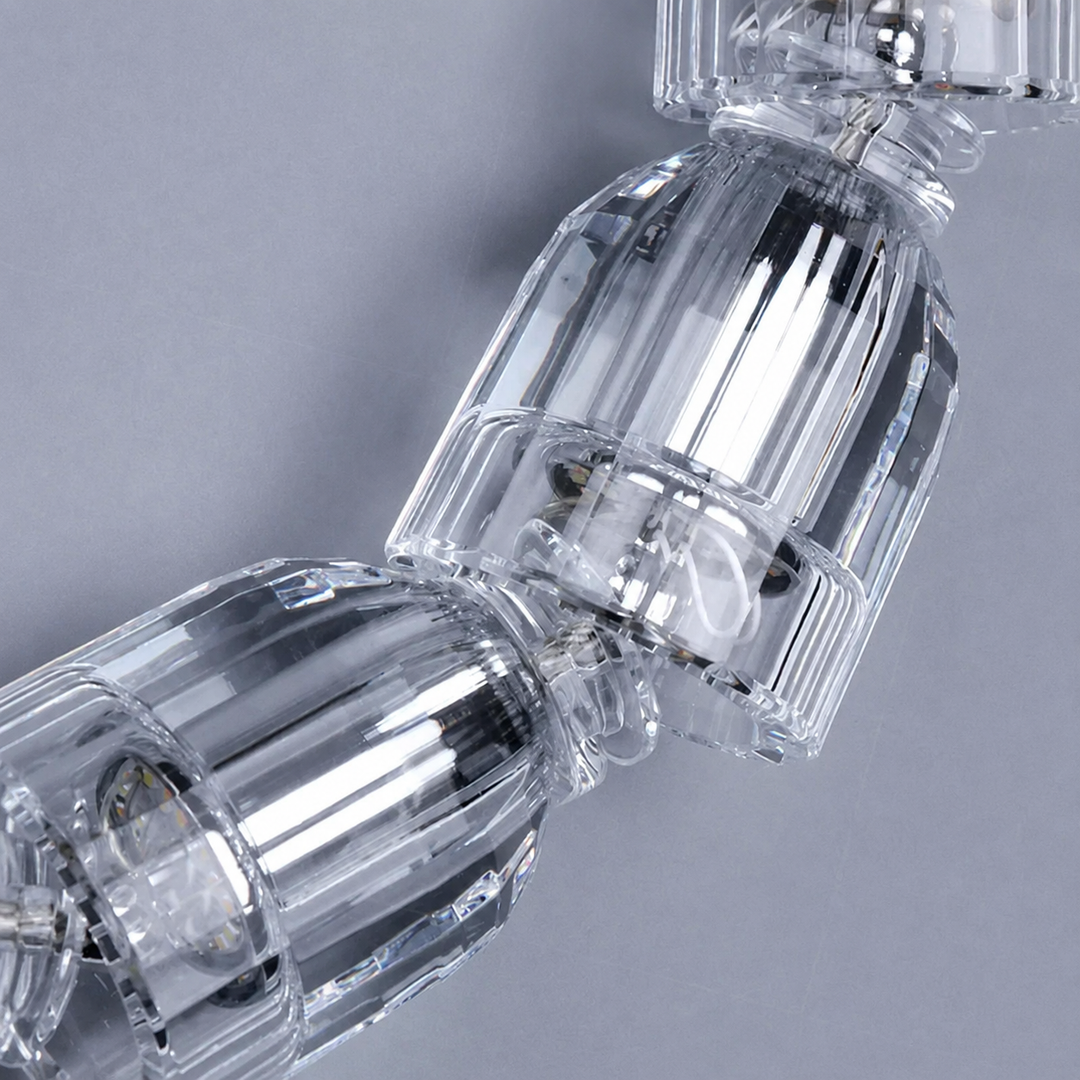 Close-up of the tiered crystal chandelier's clear faceted strands against a plain grey background.