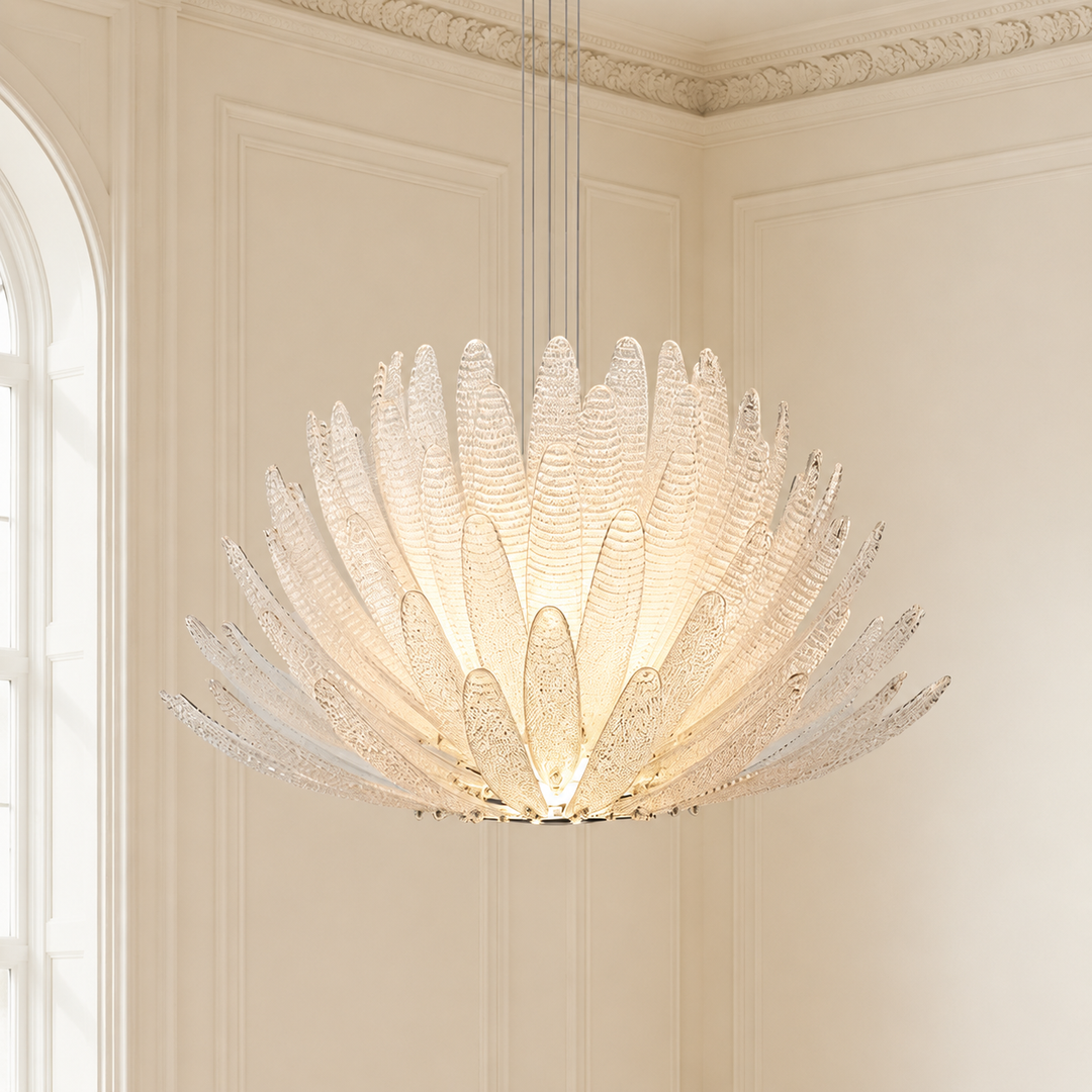 A large, modern flower-shaped chandelier with textured, petal-like clear glass shades, glowing with warm light from within, suspended in a classic cream-colored room with decorative wall paneling.