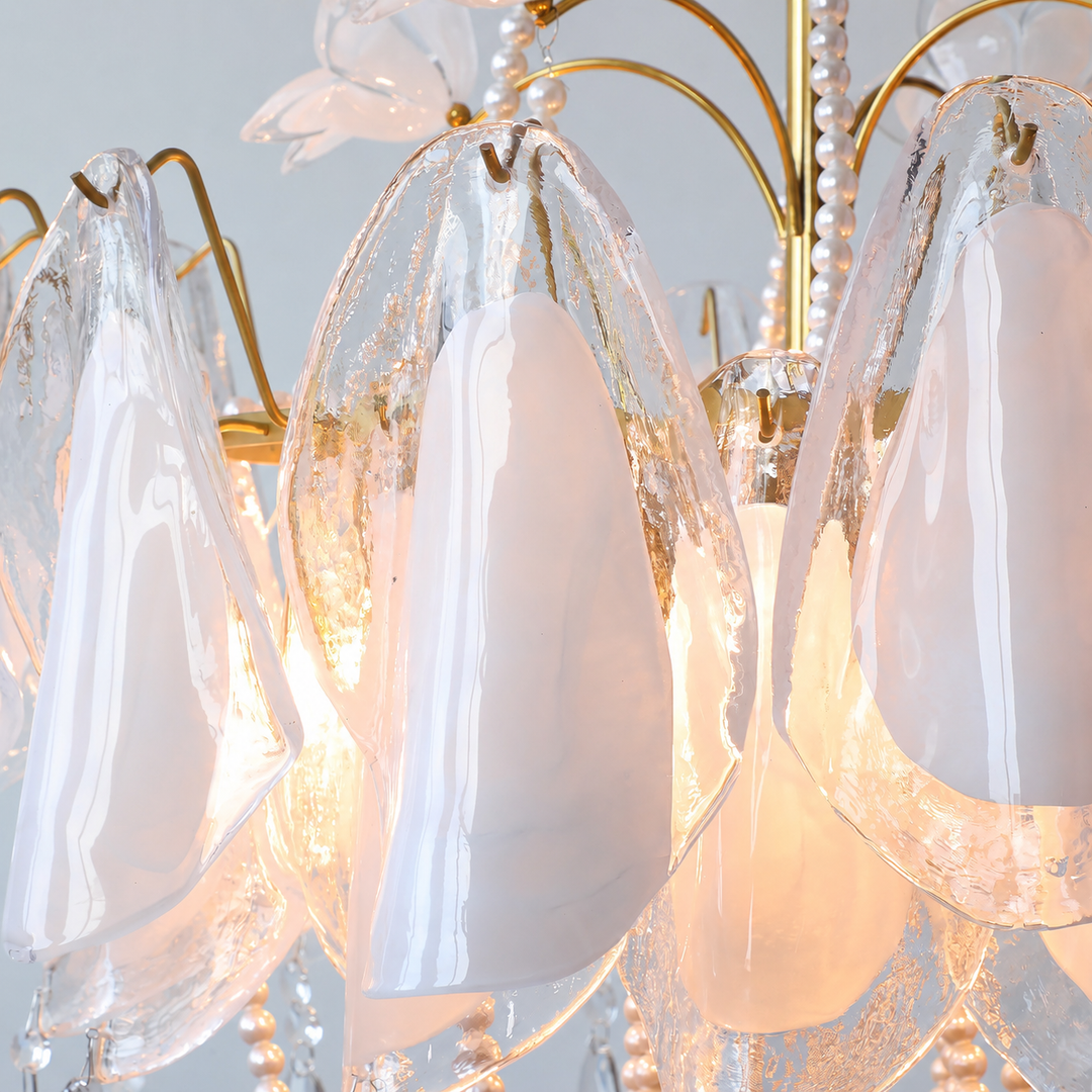 A close-up of a chandelier with teardrop-shaped translucent white glass shades, a gold metal frame, and warm glowing light inside.