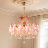 A pink and gold chandelier with translucent glass flower-shaped shades, hanging from a decorative gold ceiling canopy in a styled room with cream walls and curtains.