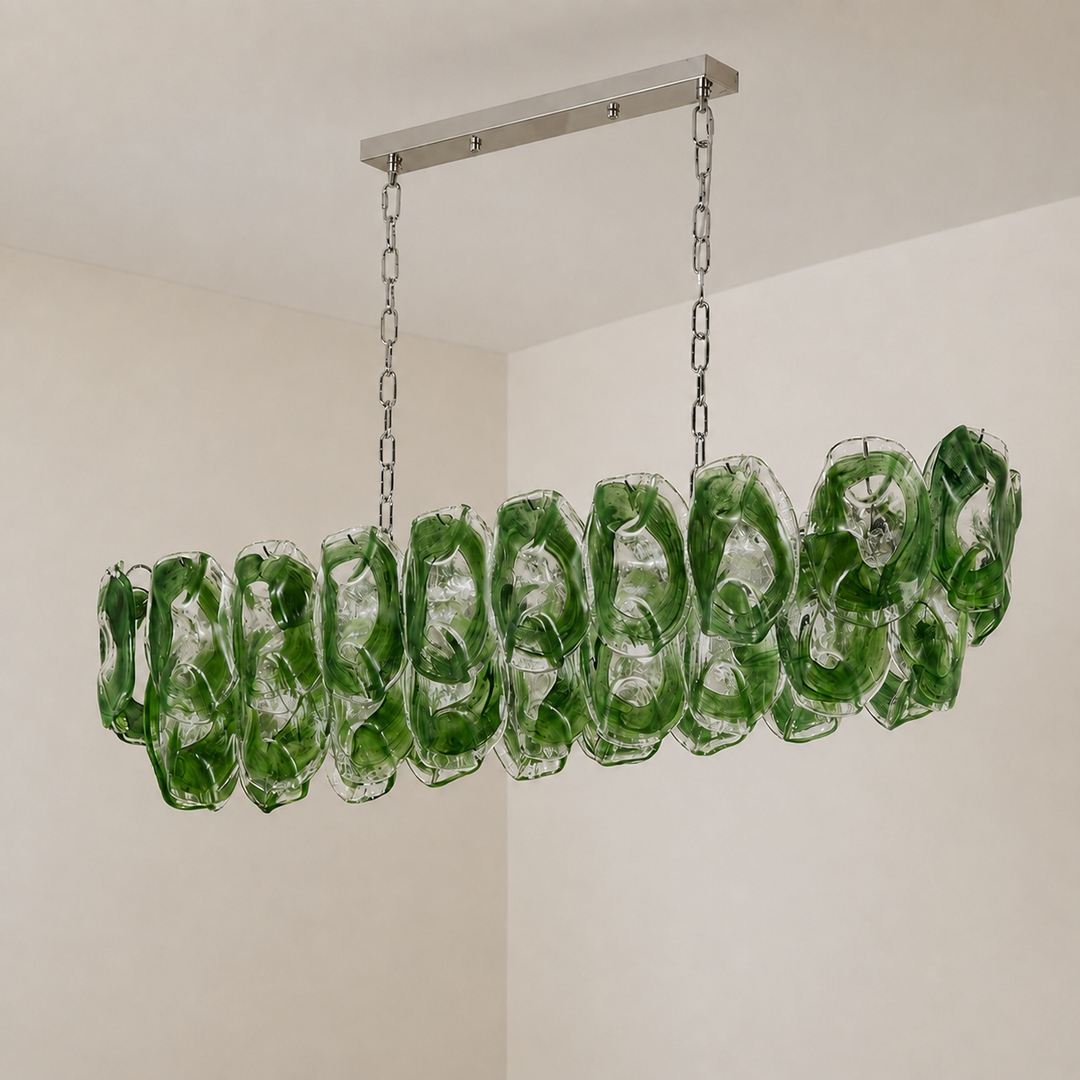 An unlit linear chandelier with overlapping green and clear glass panels hangs against cream walls.