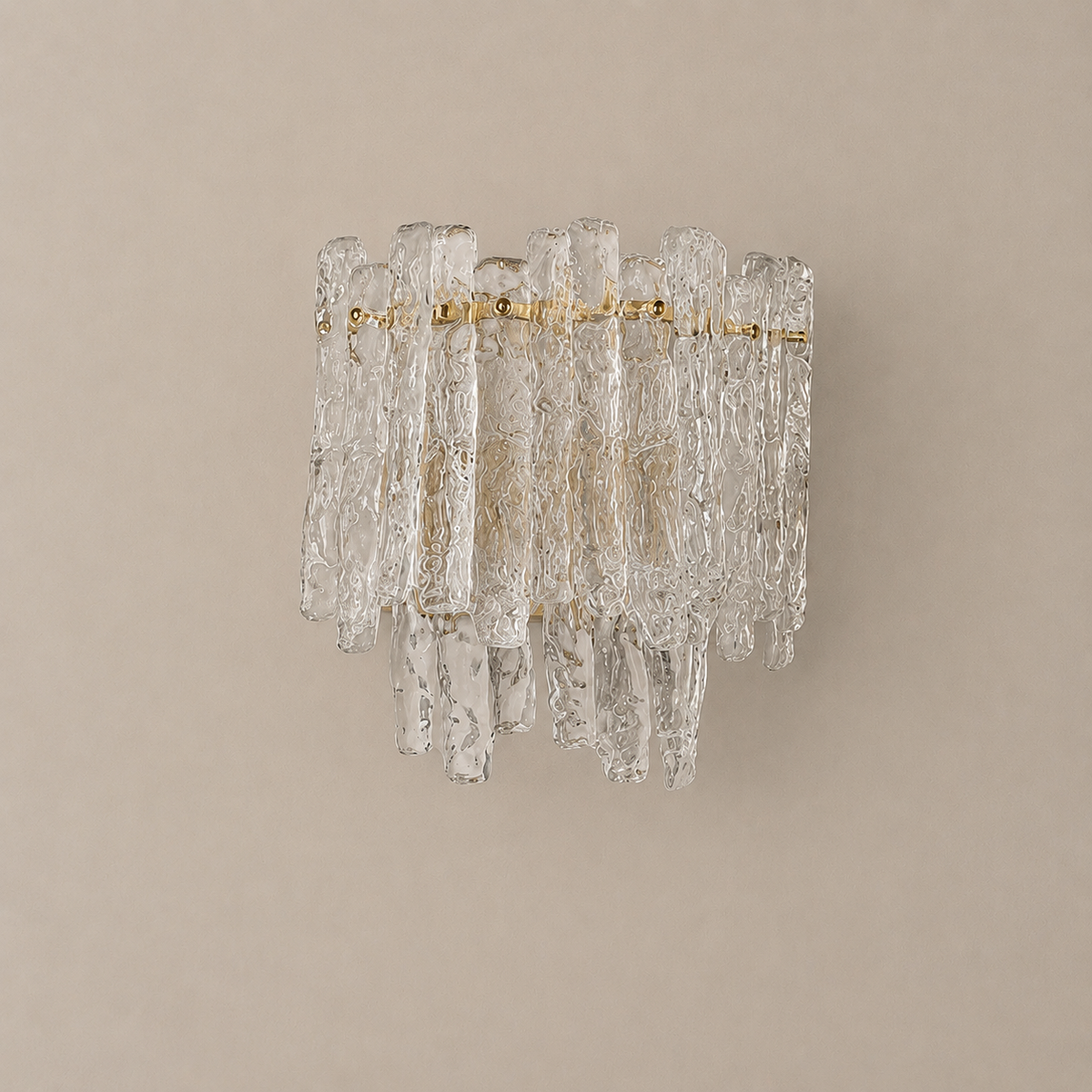 Wall sconce of hand-textured clear-to-amber glass pieces on a brass-tone frame, unlit on a plain beige wall.