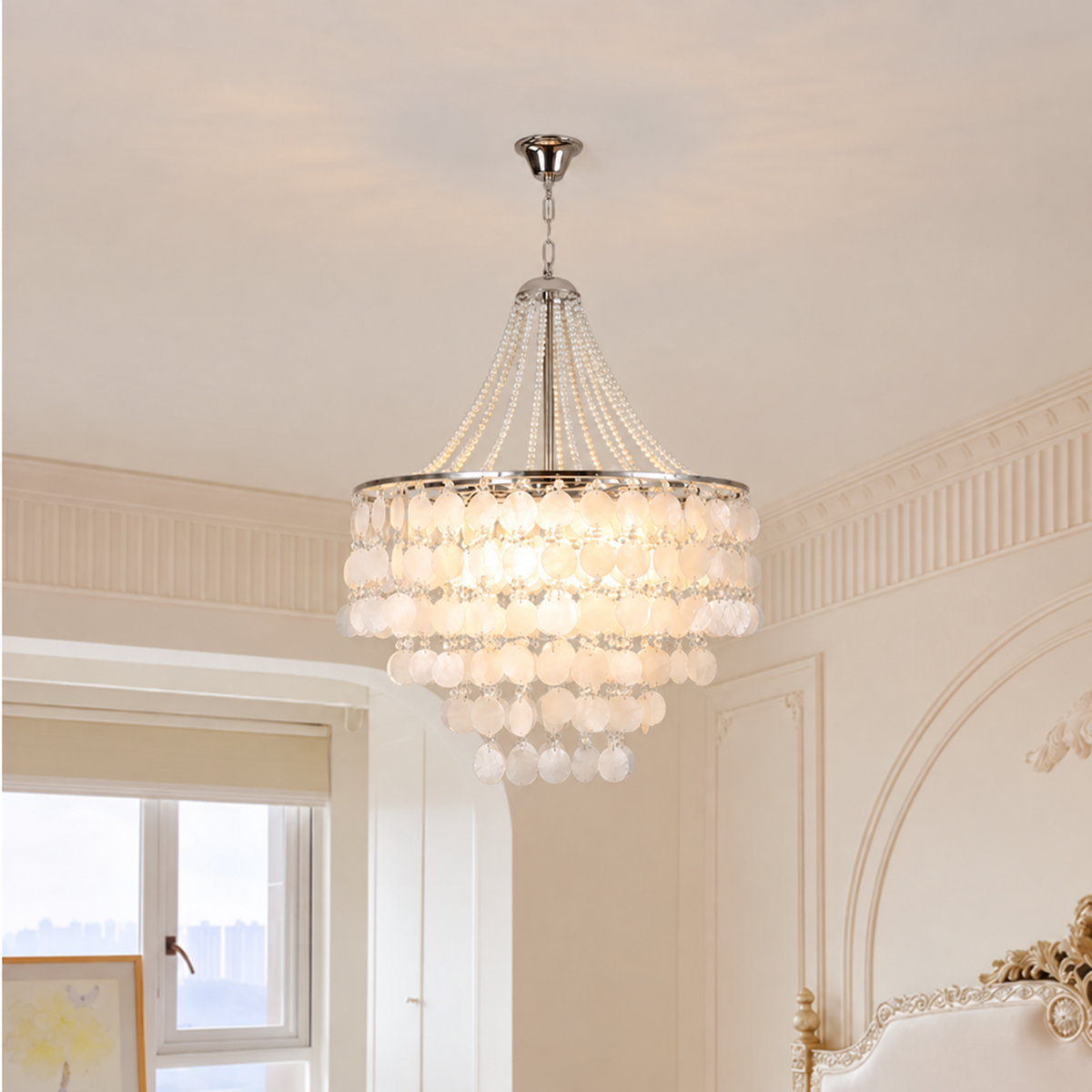 A multi-tiered crystal chandelier with a silver-toned metal frame and hanging glass beads, illuminated in a bright room with cream-colored walls and decorative molding.