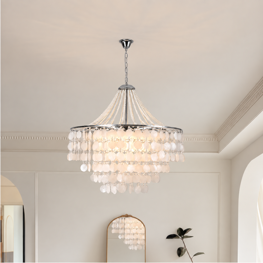 A multi-tiered crystal chandelier with a silver-toned metal frame and hanging glass beads, suspended from the ceiling in a bright, modern room.