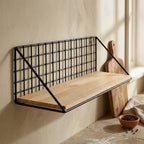 Close view of the powder coated steel wire frame meeting the solid wood base panel of the wall shelf