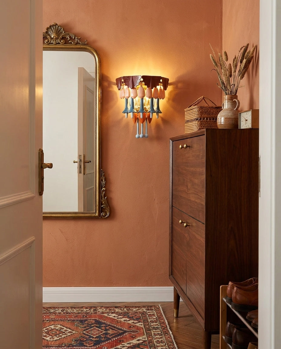 Multicolor chandelier fixture glows against a terracotta entryway wall beside an ornate mirror and a tall wooden cabinet.