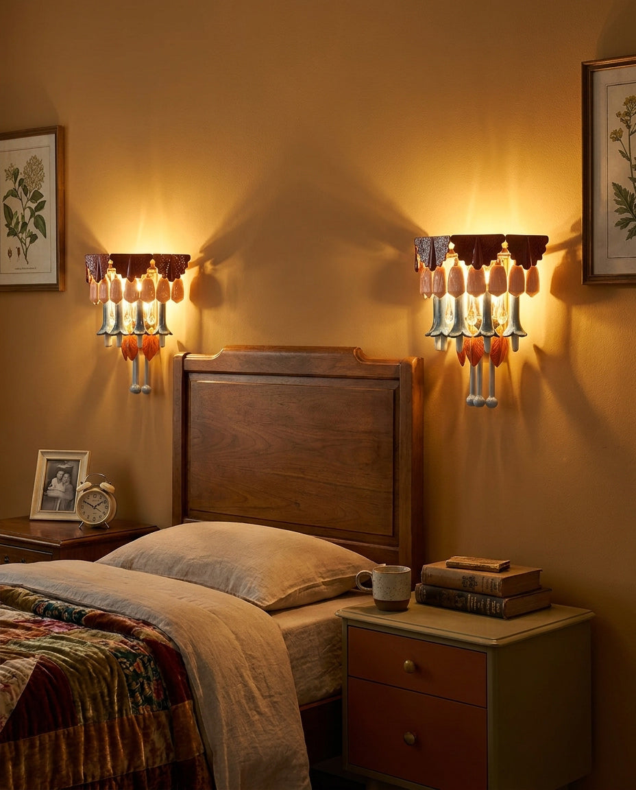 Two matching multicolor chandelier fixtures glow on either side of a wooden headboard in a bedroom with ochre walls.