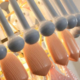 Close-up of a modern chandelier with curved white arms and ribbed peach-pink glass drops, illuminated by warm golden light.