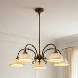 An ornate five-light chandelier with an antique bronze-finished metal frame and textured cream glass shades, hanging from the ceiling in a classic room setting.