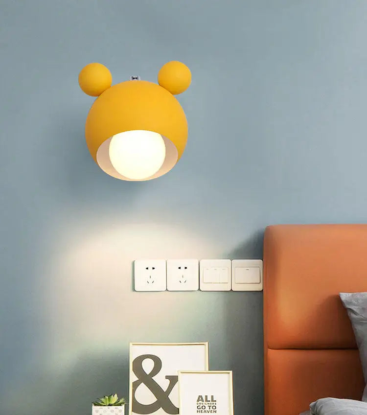 Yellow wall lamp lit on a blue wall above an orange headboard