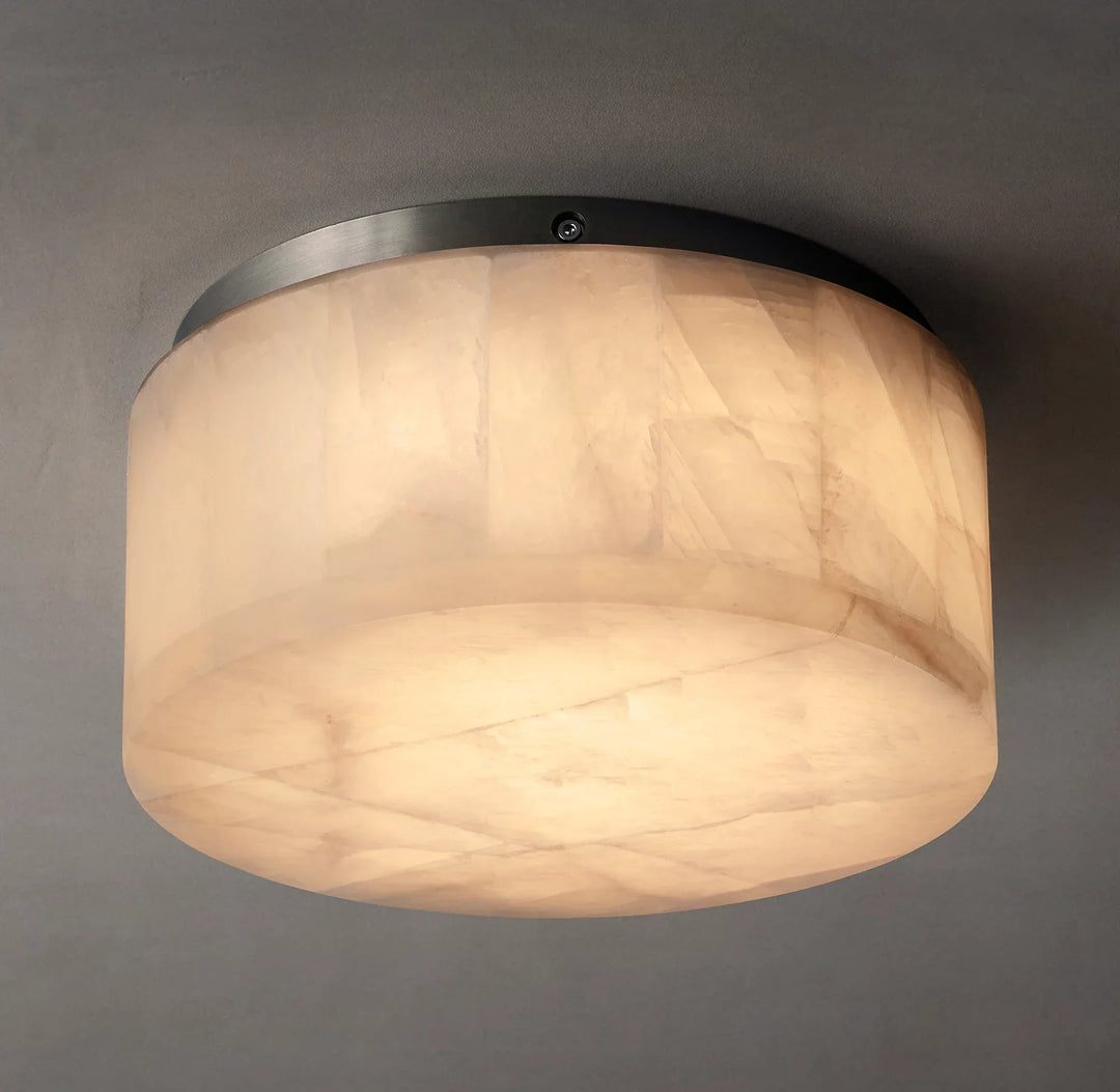 Illuminated alabaster drum flush mount light shows cream stone veining and dark ceiling trim against a gray background.