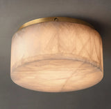 Alabaster drum flush mount light viewed from below, showing warm illumination, natural veining, and a gold-colored rim against gray.