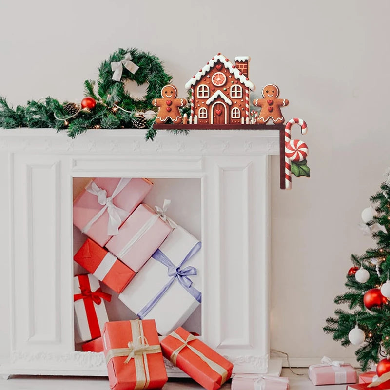 Brown gingerbread house door corner decoration rests on a white fireplace surround filled with wrapped gifts, beside green garland and a wreath.