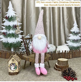 Pink long-legged gnome with a white beard sits on a wooden chair between decorative Christmas trees, with a 16 × 46.5 cm label.