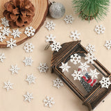 White wood snowflake ornaments surround a dark lantern on cream fabric beside a pinecone, wood slice, silver bauble, and miniature tree.
