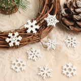 White wood snowflake ornaments rest on a brown twig wreath and cream lace beside a pinecone and green foliage.