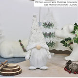 White-bearded gnome with a silver sequined hat stands among white Christmas decorations and wood slices, with a 14 × 31 cm label.