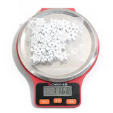 A clear bag of white wood snowflake ornaments rests on a red digital scale displaying 11.68 against a white background.