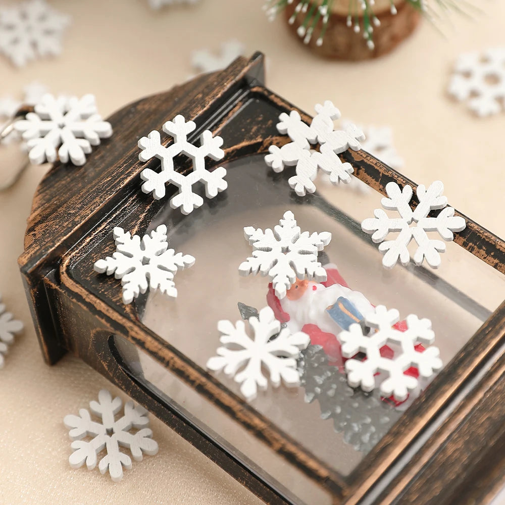 White wood snowflake ornaments decorate the glass and distressed dark frame of a lantern containing a Santa figurine.