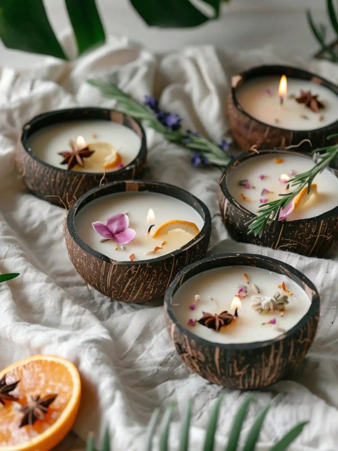 Coconut shell candles with star anise, lavender and dried flowers beside a monstera leaf