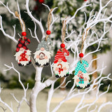 Four wooden gnome Christmas ornaments with plaid, gray polka-dot, red striped, and turquoise zigzag hats hang from white branches.
