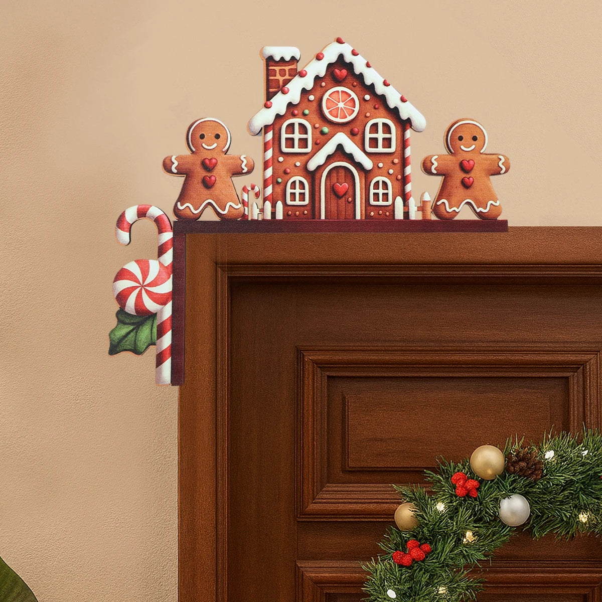 A gingerbread house corner decoration sits above a brown door, with a candy cane on the left and part of a wreath below.