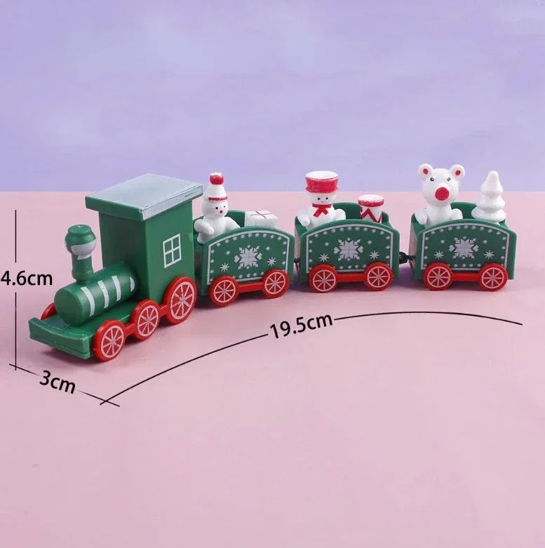 Green Christmas train decoration with red wheels and three connected carriages on pink, labeled 19.5 cm long, 4.6 cm high, and 3 cm wide.