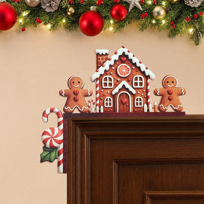 Brown gingerbread house door corner decoration with two smiling figures and a hanging candy cane sits on a wooden doorframe beneath garland.