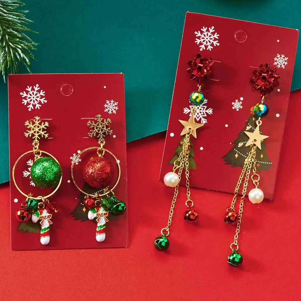 Christmas drop earrings with red bows, gold-tone stars, glitter balls and candy canes on red snowflake cards against red and teal backgrounds.
